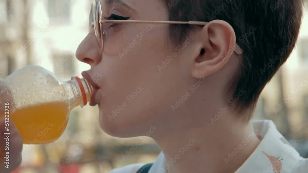 Close up of a young woman laughing outdoors and drinking soda Close up of a young woman laughing outdoors and drinking soda