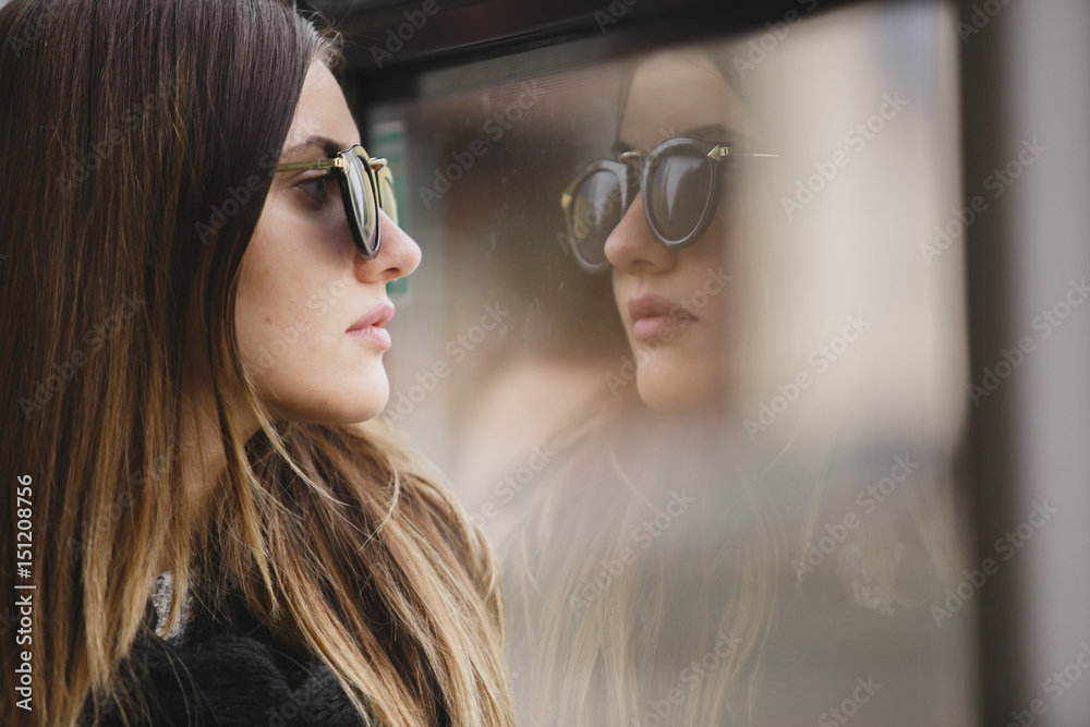 Girl in sunglasses stands at the window of the bus and dreams Girl in sunglasses stands at the window of the bus and dreams