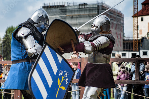 Knight tournament. The knights in the congregations are fighting in the ring. Public event in the city. Soldiers in armor of the Middle Ages.