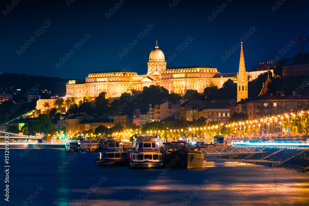 Evening view of Buda Castle with city lights and ship on the Danube river