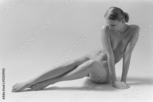 Beautiful blonde nude woman sitting on white background. Black & white film. Film grain. Copy space for text. photo