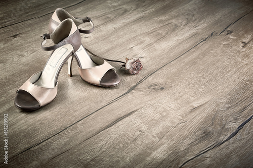 Argentine tango shoes with a rose on wooden floor, space