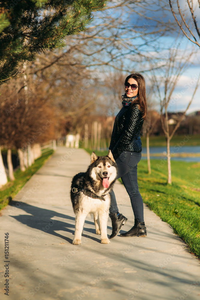 A girl is walking with a dog along the embankment. Beautiful Husky dog. The river. Spring. A girl is walking with a dog along the embankment. Beautiful Husky dog. The river. Spring.