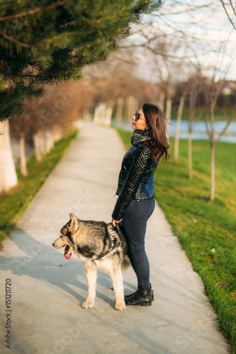 A girl is walking with a dog along the embankment. Beautiful Husky dog. The river. Spring. © Aleksandr