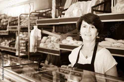 middle-aged female baker with fresh bread in bakery