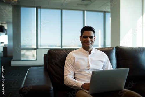 Businessman using laptop while sitting of sofa in office © wavebreak3