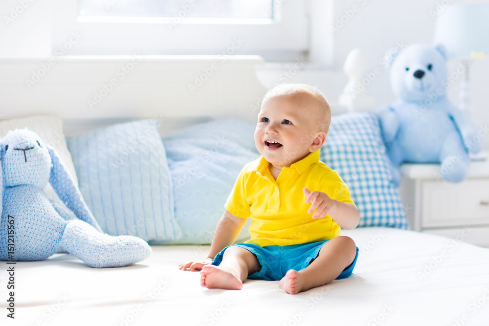 Baby boy playing on bed in sunny nursery Baby boy playing on bed in sunny nursery