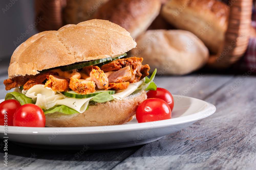 Fried chicken meat with cheese and vegetables in bun Fried chicken meat with cheese and vegetables in bun