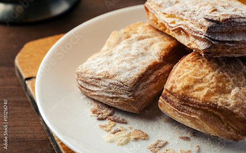 Puff pastries in a white plate with crumbs closeup shot