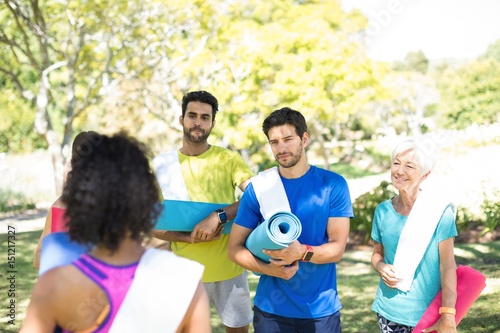 People with rolled exercise mats talking in the park  © WavebreakMediaMicro