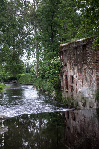 Scene from another era  an old mill in the park with the river placid flowing 