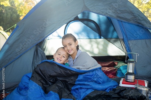 Happy siblings sitting in the tent
