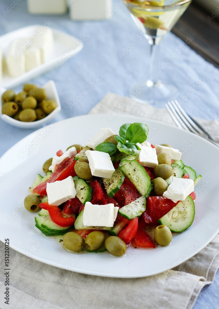 Greek salad with fresh vegetables, feta cheese and green olives on blue background