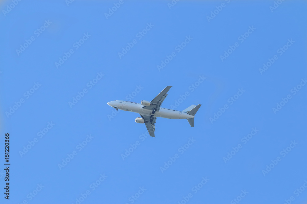White passenger plane flies highly in the sky on a bright Sunny day without clouds White passenger plane flies highly in the sky on a bright Sunny day without clouds