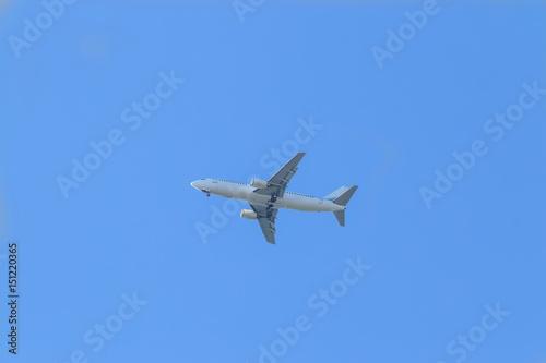 White passenger plane flies highly in the sky on a bright Sunny day without clouds
