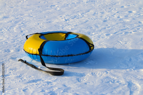 Yellow and blue new snowtube is on white snow at winter sunny day