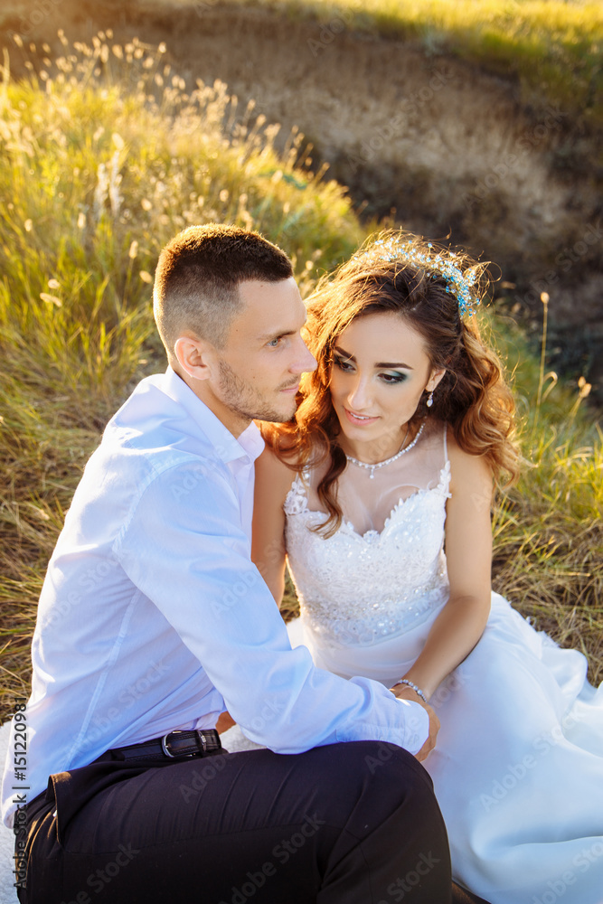 Beautiful couple in field, Lovers or newlywed posing on sunset with perfect sky Beautiful couple in field, Lovers or newlywed posing on sunset with perfect sky
