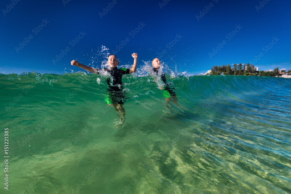 Boys swimming and playing with large ocean waves