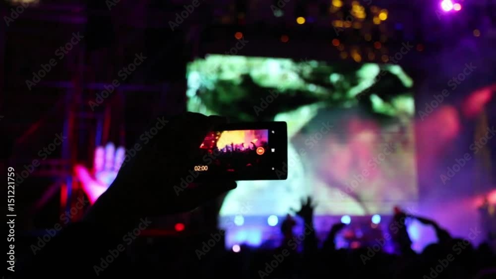Hand with cell phone for shooting at concert with illumination, focus on hand Hand with cell phone for shooting at concert with illumination, focus on hand