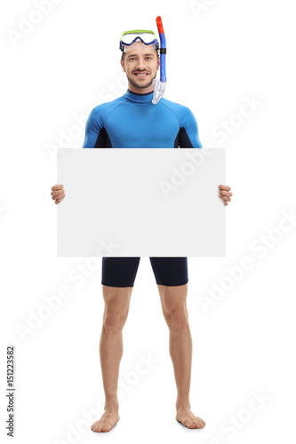 Young man with snorkeling equipment holding a blank signboard