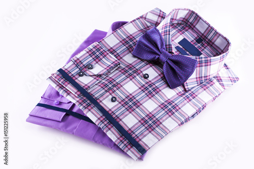 Two shirts folded and a bow tie on a white background