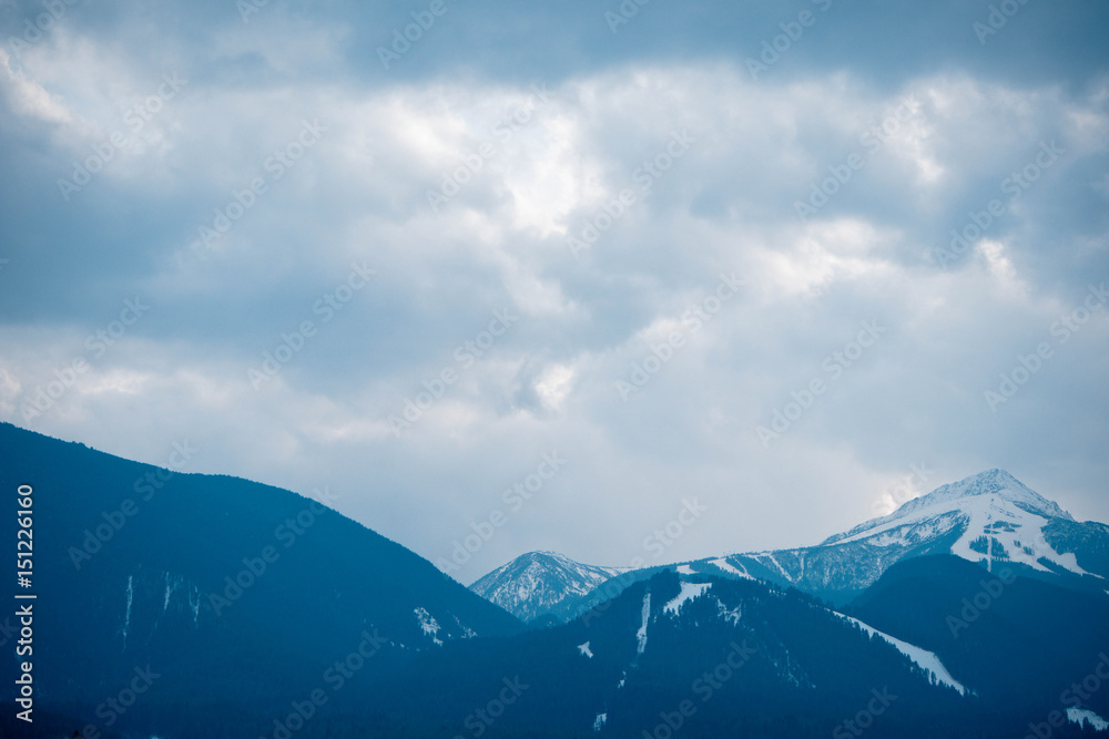 Photo depicting a beautiful moody frosty landscape European alpine mountains with snow peaks on a blue sky background.