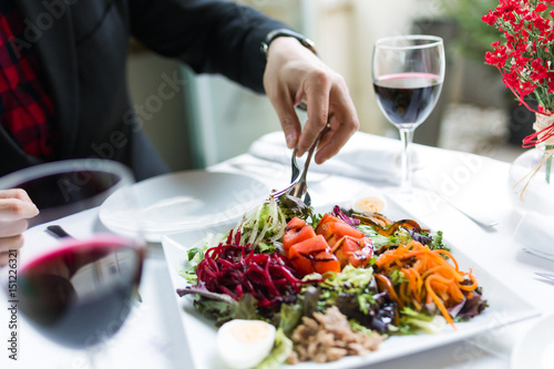 Handsome young man serving salad on a plate in the restaurant.