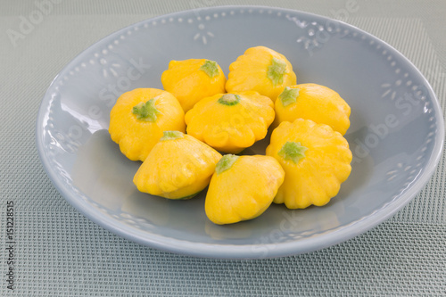 Fresh yellow patissons on a gray plate. Miniature food