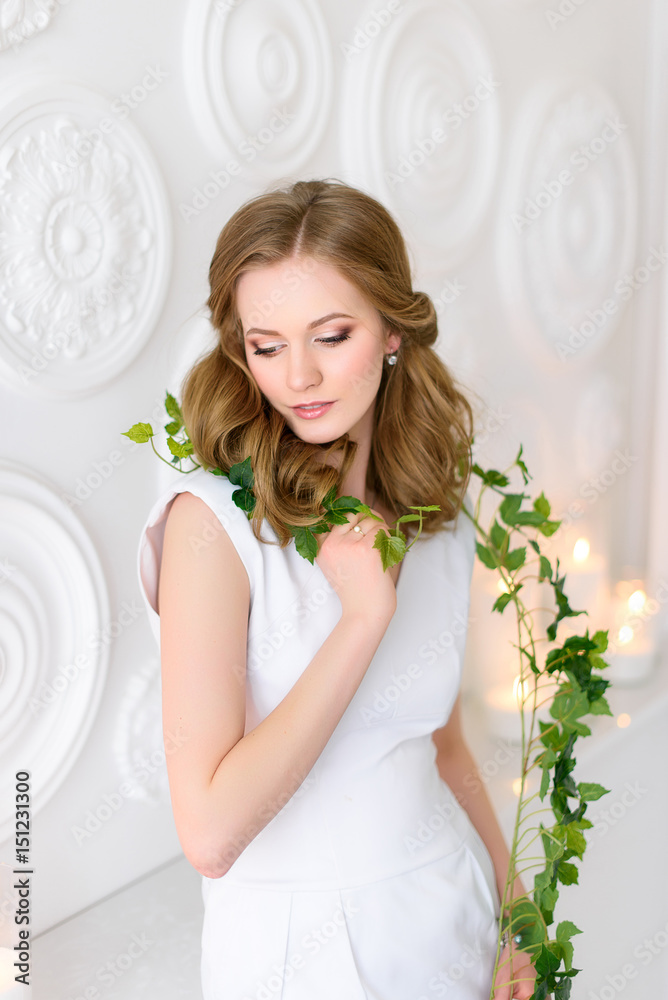 A naturally beautiful young woman with a long green branch in her hands, eyes down shyly. Health and beauty concept. A naturally beautiful young woman with a long green branch in her hands, eyes down shyly. Health and beauty concept.