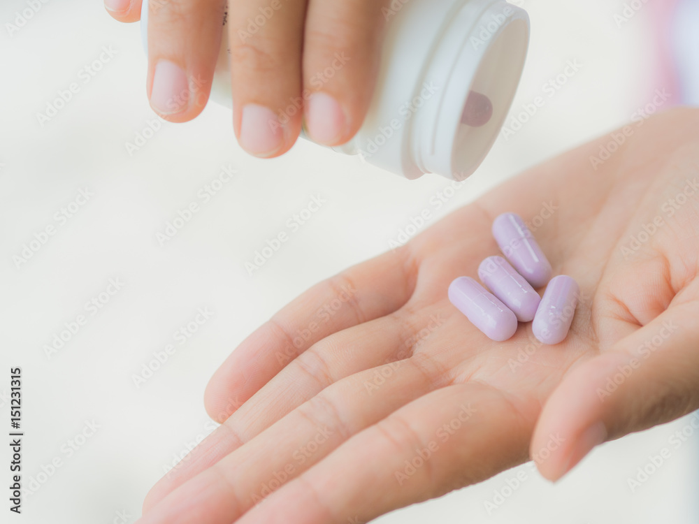 A young woman pours out medicine into her hand A young woman pours out medicine into her hand