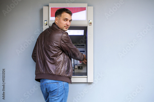 Young man inserting a credit card to ATM