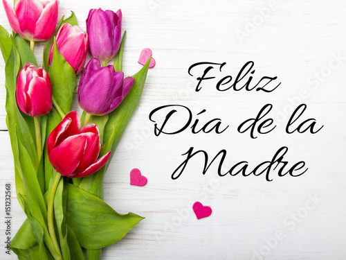 Mother's day card with Spanish words: Happy Mother's day, and  tulip bouquet on white wooden background
