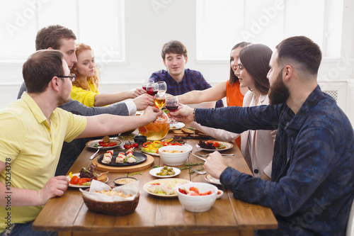 People say cheers clink glasses at festive table dinner party