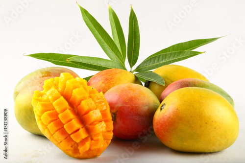Tropical fresh mangoes with leaves on white background.