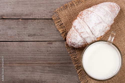 glass of milk with croissants on old wooden background with copy space for your text. Top view