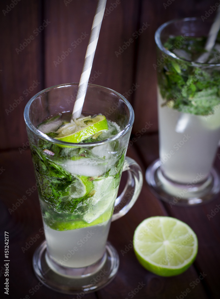 Homemade cocktail with lime and mint on wood background Homemade cocktail with lime and mint on wood background