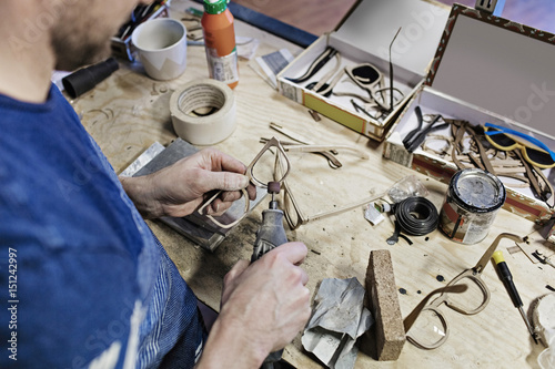High angle view of owner making eyeglasses with work tool at workshop