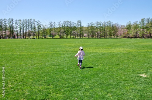 芝生の広い公園を走る子供