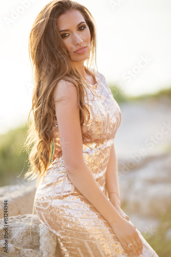 Beautiful tender woman posing on the sunset beach