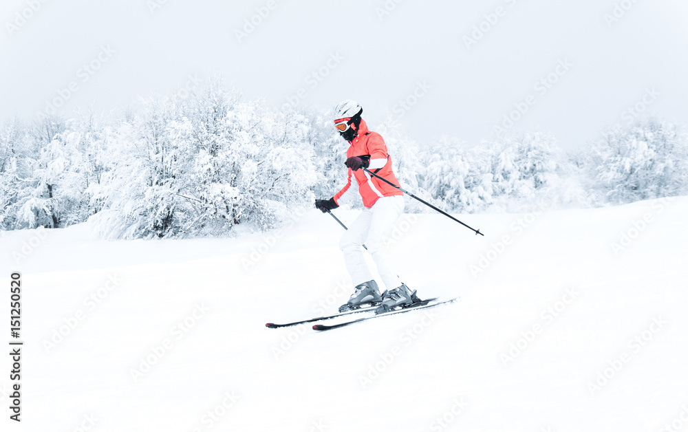 Woman skier skiing downhill on ski piste