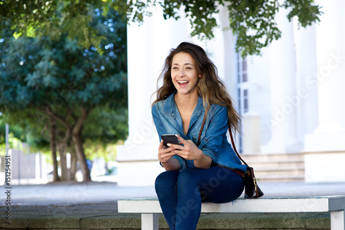 happy young woman laughing and holding mobile phone
