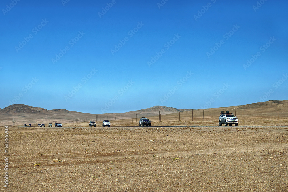 Obraz premium Fahrzeugkonvoi durch die Namibische Wüste