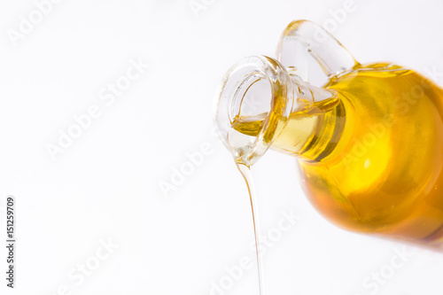 Pouring virgin olive oil in a crystal bottle isolated on white background. Copyspace.