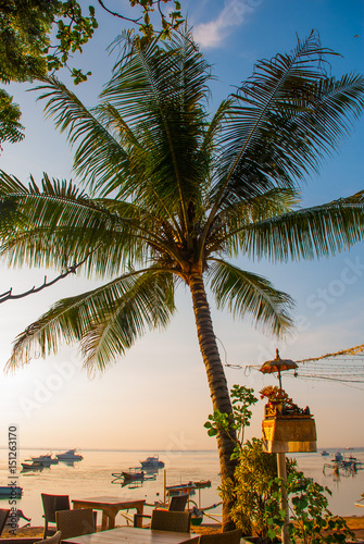 Beautiful beach with a cafe in Sanur with local traditional boats Palm trees on the island of Bali at dawn. Indonesia