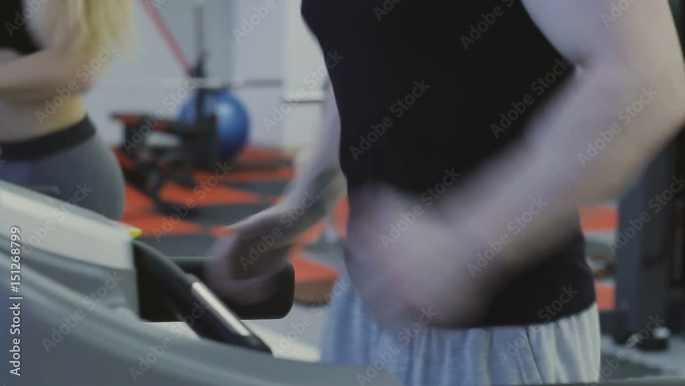 A man and a girl are training on a treadmill in a fitness club A man and a girl are training on a treadmill in a fitness club