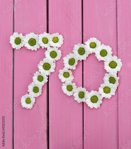 Number seventy in daisy heads on a pink background of painted wooden boards, burthday image 