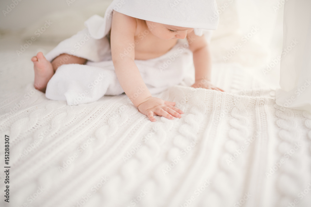 beautiful smiling newborn baby boy covered with white bamboo towel with fun ears. Sitting on a white knit, wool plaid bright interior. The ight from the window beautiful smiling newborn baby boy covered with white bamboo towel with fun ears. Sitting on a white knit, wool plaid bright interior. The ight from the window