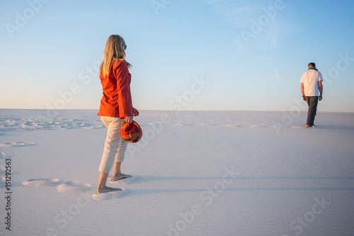 Man and a young beautiful woman go one by one in the desert