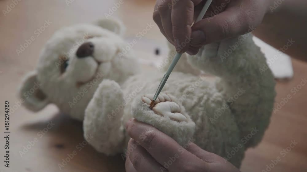 A thin brush in the hands of the artist to create soft toys. The master