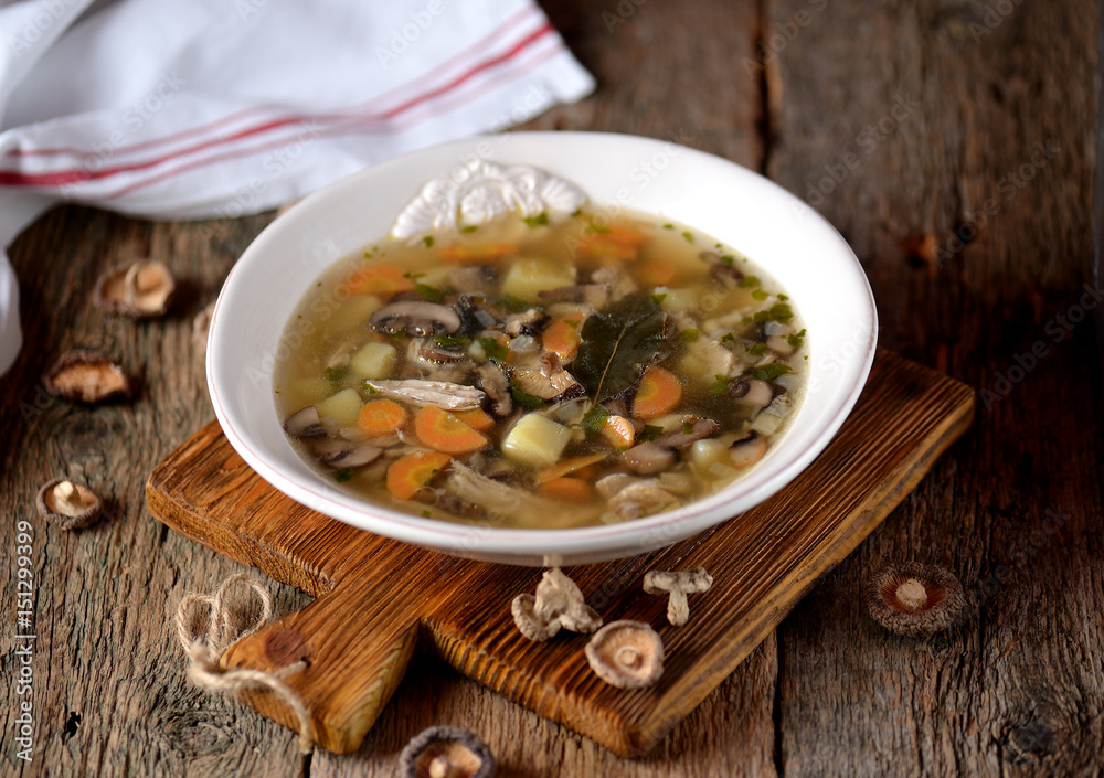Mushroom soup with potatoes, carrots, onions and chicken meat on an old wooden background. Rustic style. Mushroom soup with potatoes, carrots, onions and chicken meat on an old wooden background. Rustic style.